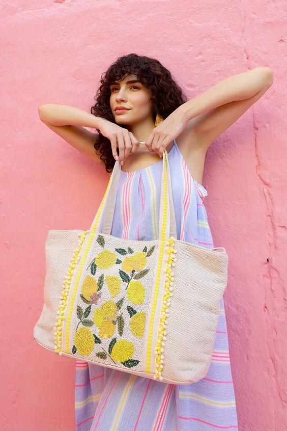 a girl wearing a long dress holding a large tote bag